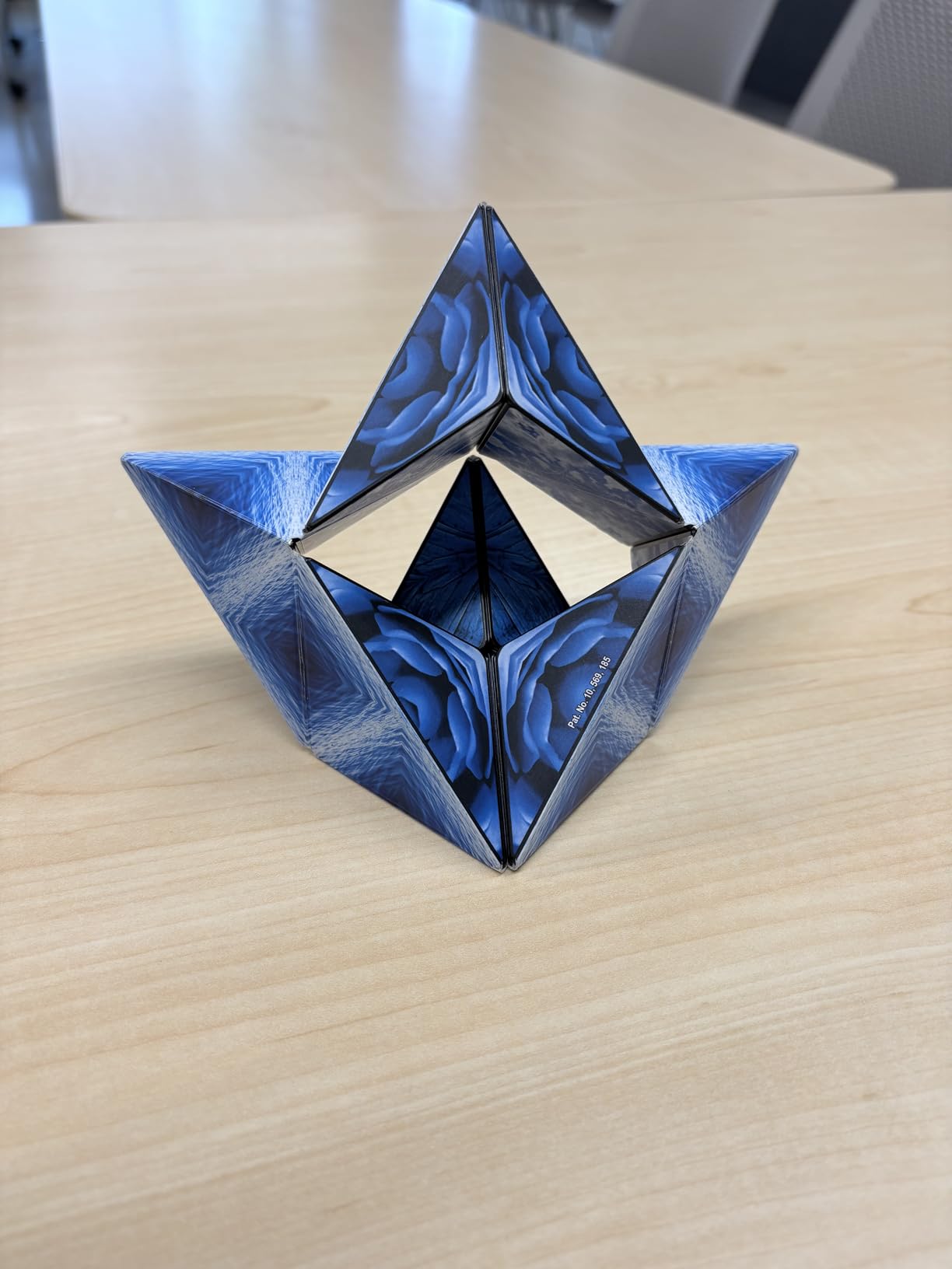 Customer photo of a blue Shashibo folded into an open star with a hollow center, resting on a light wood desk