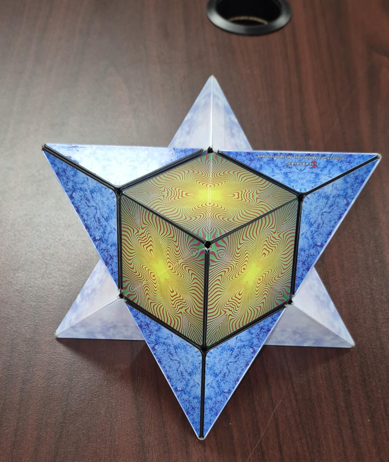 Customer photo of a blue and white Shashibo folded into a six-pointed star around a yellow and green center